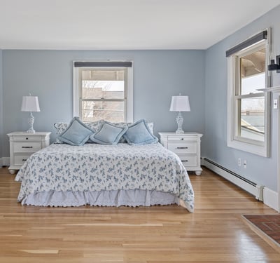 Spacious master bedroom featuring cozy decor, large windows, and a classic brick fireplace for warmth.