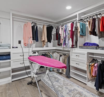 Spacious walk-in closet equipped with ample storage and a convenient ironing station for modern living.