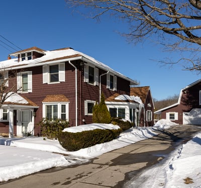 Spacious four-bedroom home with inviting exterior, expansive driveway, and a large garage on a snowy lot.