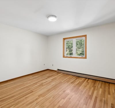 Spacious room featuring hardwood floors and a bright window, perfect for personalization and creativity.