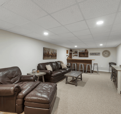 Spacious finished basement features cozy seating, a bar area, and modern lighting, perfect for entertaining.