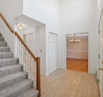 Spacious entryway with a graceful staircase leads to a versatile living area and abundant natural light.