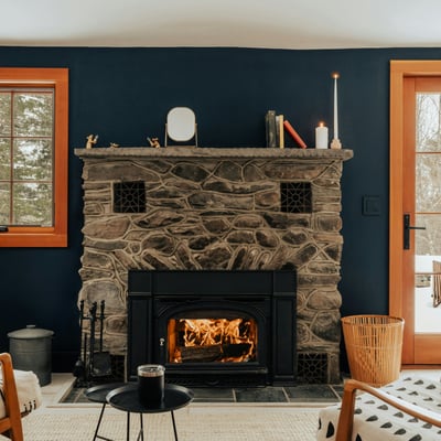 Cozy living area featuring a stone fireplace, large windows, and direct access to a snowy outdoor space.
