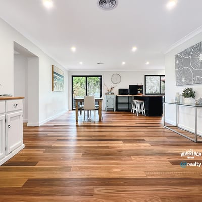 Spacious open-concept living area with warm wooden floors and abundant natural light, ideal for entertaining.