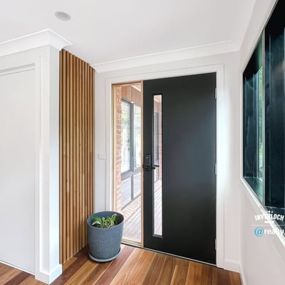 Contemporary entryway featuring a sleek front door and natural light enhancing the warm wooden floors.