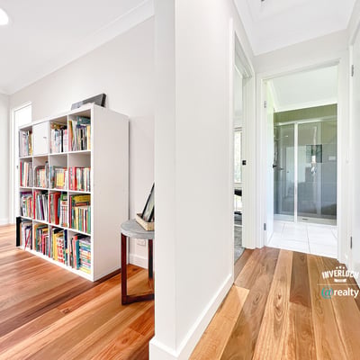 Bright and inviting interior featuring wooden floors, a spacious hallway, and a versatile bookshelf area.