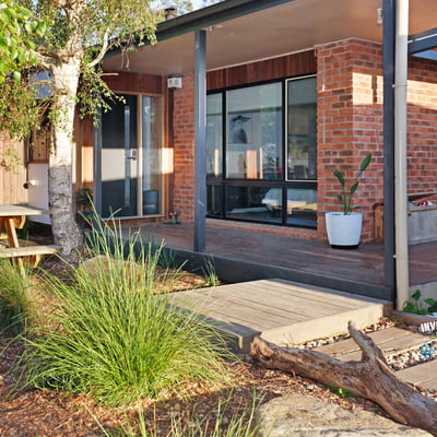 Contemporary home featuring expansive windows and an inviting outdoor space surrounded by lush greenery.