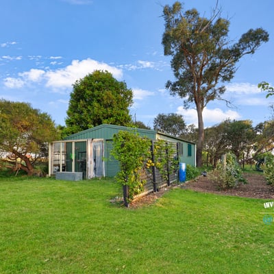 This property features a spacious backyard with greenery and a versatile outbuilding, perfect for various uses.
