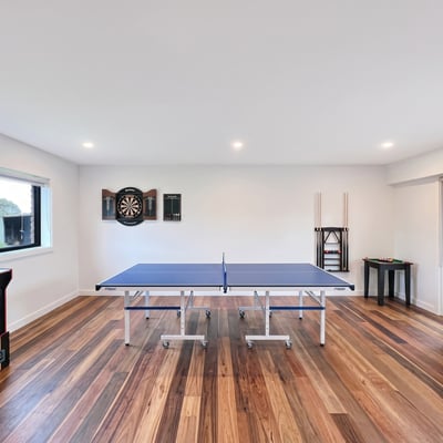 Bright recreational space featuring a ping pong table, arcade machine, and dartboard for entertainment.