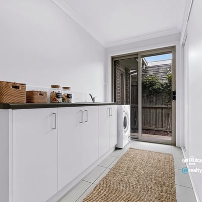 Light-filled laundry room featuring ample storage, modern appliances, and direct access to an outdoor area.
