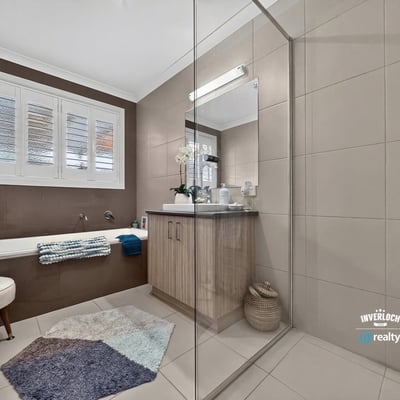 Modern bathroom featuring a spacious walk-in shower, double vanity, and natural light from large windows.