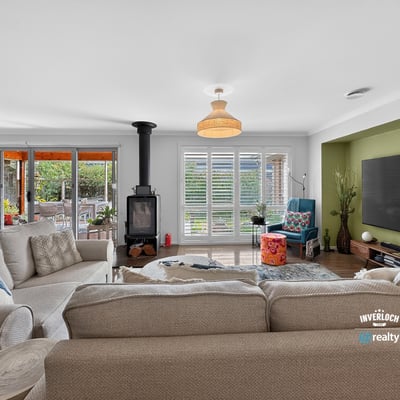 Spacious living area with a cozy stove, large windows, and bright natural light throughout.
