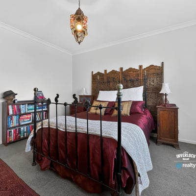 Cozy bedroom featuring a unique wooden headboard, warm lighting, and an inviting atmosphere for relaxation.