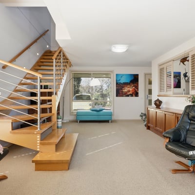 Spacious living area with inviting staircase and large windows offering ample natural light.