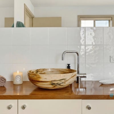 Discover a beautifully designed bathroom featuring a unique stone sink and warm, inviting accents.