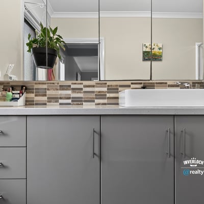 Modern bathroom featuring sleek cabinetry, contemporary fixtures, and a unique mosaic tile backsplash.