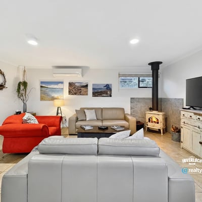 Spacious living area features comfortable seating and a cozy wood stove, perfect for relaxation and gatherings.