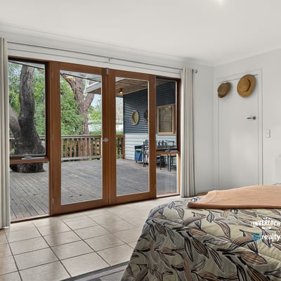 Bright and spacious bedroom with large sliding doors opening to a private outdoor deck area.
