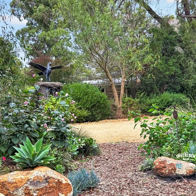 Lush garden space featuring native plants, rock formations, and a unique sculpture, perfect for outdoor relaxation.