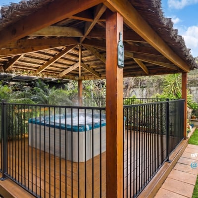 Relax in this private outdoor gazebo featuring a hot tub, surrounded by lush greenery.