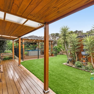 Discover a spacious outdoor oasis featuring sleek decking, vibrant greenery, and a refreshing pool area.