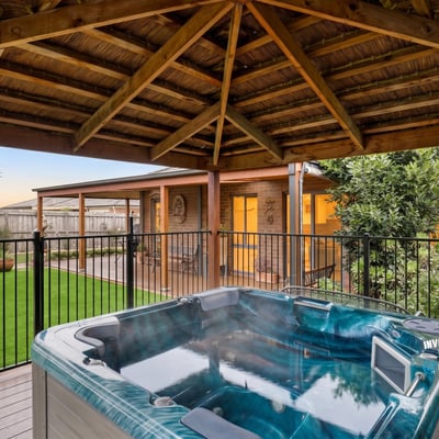 Relax in the inviting hot tub surrounded by lush landscaping and a spacious outdoor retreat.
