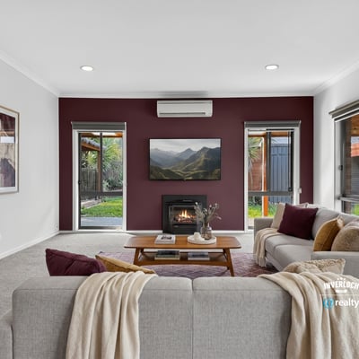 Cozy living room with modern features, featuring a fireplace and large windows overlooking a private outdoor space.