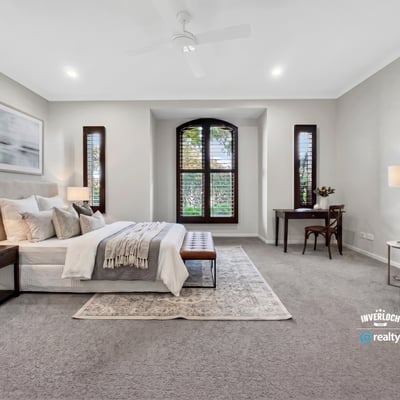 Spacious master bedroom featuring large windows, plush carpeting, and a cozy reading nook.