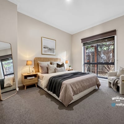 Bright and inviting bedroom featuring large windows, modern decor, and a cozy reading nook for relaxation.