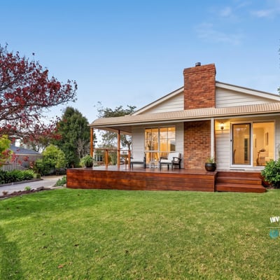 Nestled on a spacious lawn, this home features a welcoming porch and abundant outdoor greenery.