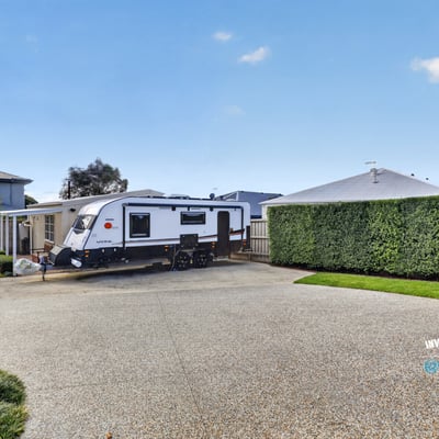 Spacious driveway perfectly accommodates an RV, surrounded by well-maintained landscaping for added privacy and convenience.