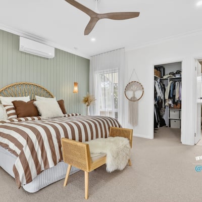 Spacious bedroom featuring unique decor, natural light, and convenient access to an organized closet and bathroom.