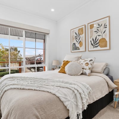 Bright and inviting bedroom featuring large windows, modern decor, and a cozy atmosphere for relaxation.