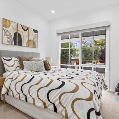 Bright bedroom featuring large windows, modern decor, and a cozy layout, ideal for relaxation and rest.