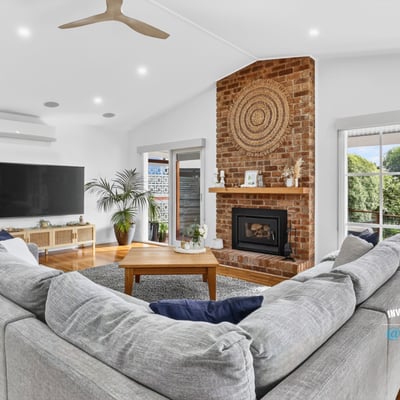 Spacious living area features a cozy fireplace, ample natural light, and direct access to outdoor views.