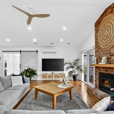 Bright and inviting living space featuring a striking brick fireplace and modern ceiling fan, perfect for gatherings.