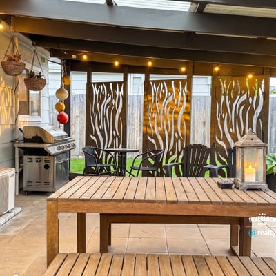 Discover an inviting outdoor space featuring a cozy dining area, grill, and decorative privacy screens.