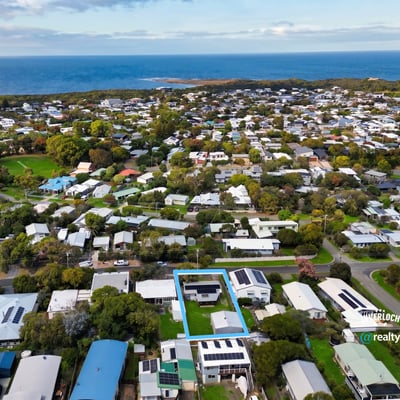 Discover a prime coastal property surrounded by lush greenery and modern homes, just steps from the shoreline.