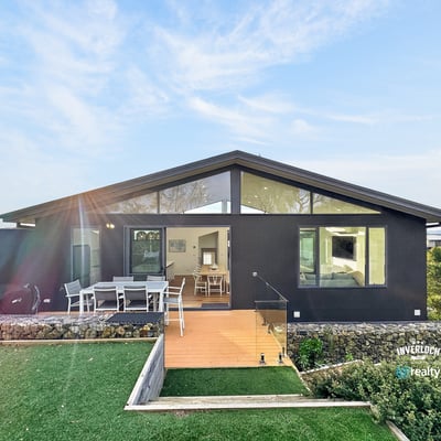Contemporary home featuring expansive windows and a spacious outdoor deck, perfect for entertaining and relaxation.