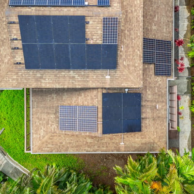 This energy-efficient home features a modern design with solar panels and lush surrounding greenery.