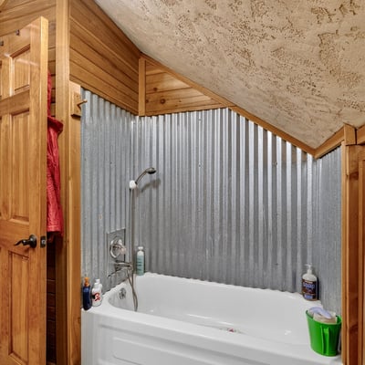 Cozy bathroom featuring a unique corrugated metal accent wall and a comfortable tub for relaxation.