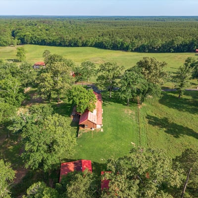 Spacious property featuring a cozy home surrounded by lush greenery and expansive fields, perfect for outdoor enthusiasts.