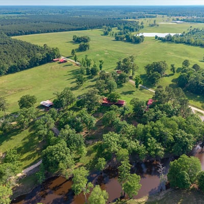 Expansive rural property featuring lush pastures, scenic water views, and multiple outbuildings for versatile use.