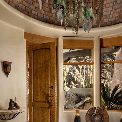 Greet guests with artisan craftsmanship at every turn starting with this custom-carved front door and original Soleri bell chandelier. A captivating welcome that sets the tone for the home s unique design throughout.