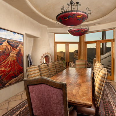 Natural light floods this beautifully curved dining space, which opens to the outdoors for seamless entertaining. Unique lighting fixtures, custom flooring, and mountain views elevate every meal to an experience.