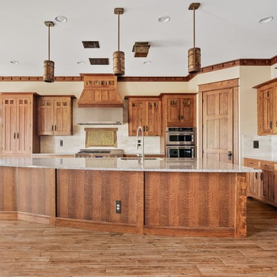 Rich wood cabinetry, detailed millwork, built-in appliances, and a striking range hood define this custom kitchen, delivering both visual appeal and everyday practicality in this Phoenix home.