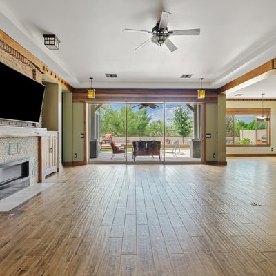 The open floor plan connects living spaces with warmth and elegance, featuring wood floors, beamed ceilings, and seamless transitions ideal for modern Phoenix living.