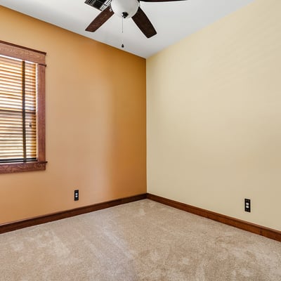 Whether used as a den, guest room, or quiet reading nook, this intimate space offers cozy carpet and natural tones with timeless window trim.