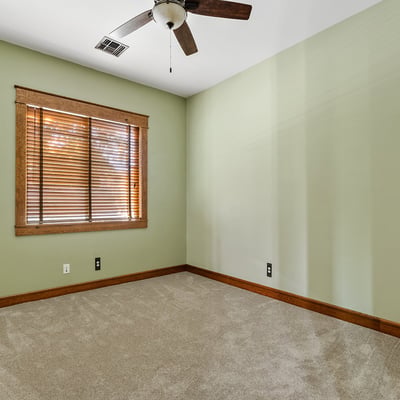 Featuring green walls, soft carpeting, and a ceiling fan, this secondary bedroom offers comfort and charm in a tranquil corner of the house.