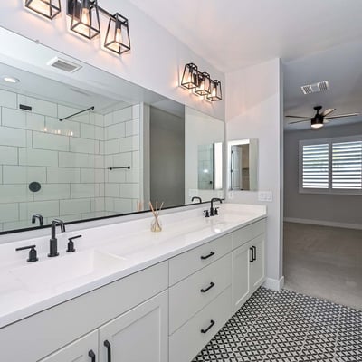 This primary bath features dual vanities, designer lighting, matte black hardware, and a spacious glass walk-in shower for a relaxing, modern feel.